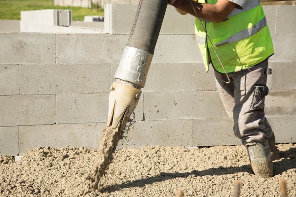 Worker manipulating a concrete filling machine on a construction site